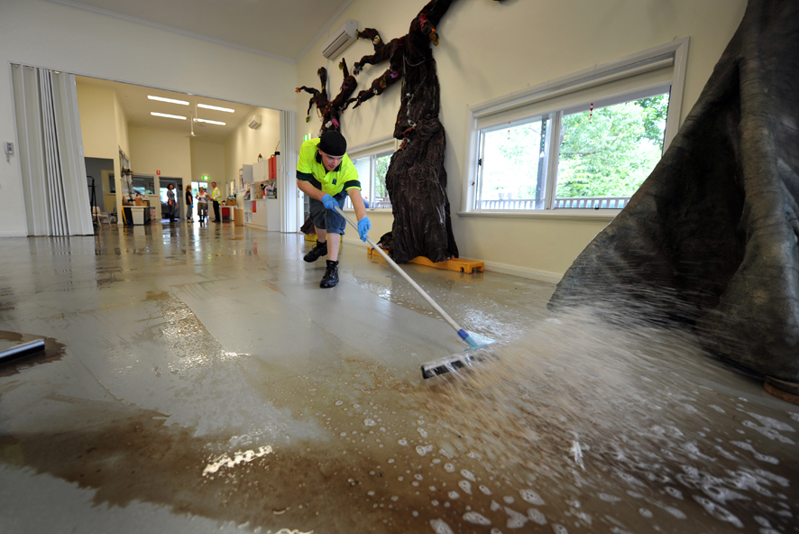 Council Waste Services staff Ryan Sellars helps clean out the floodwaters from the Jamberoo Preschool.