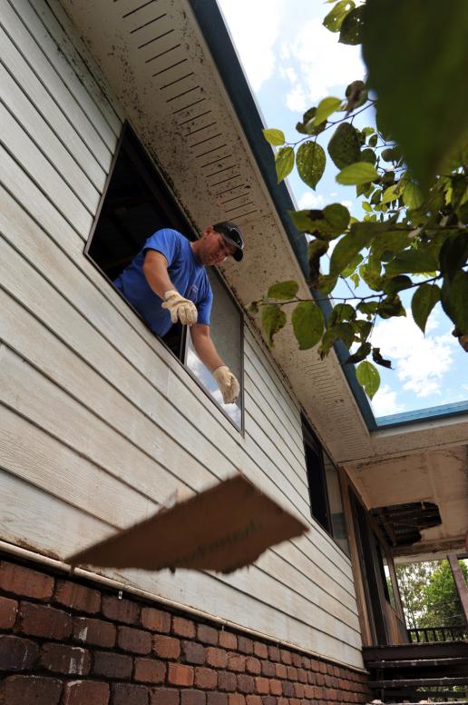 Global Care Volunteer Craig Knowles of Horsley, throws sheets of wet gyprock out the window of a house in North Booval, Queensland.
