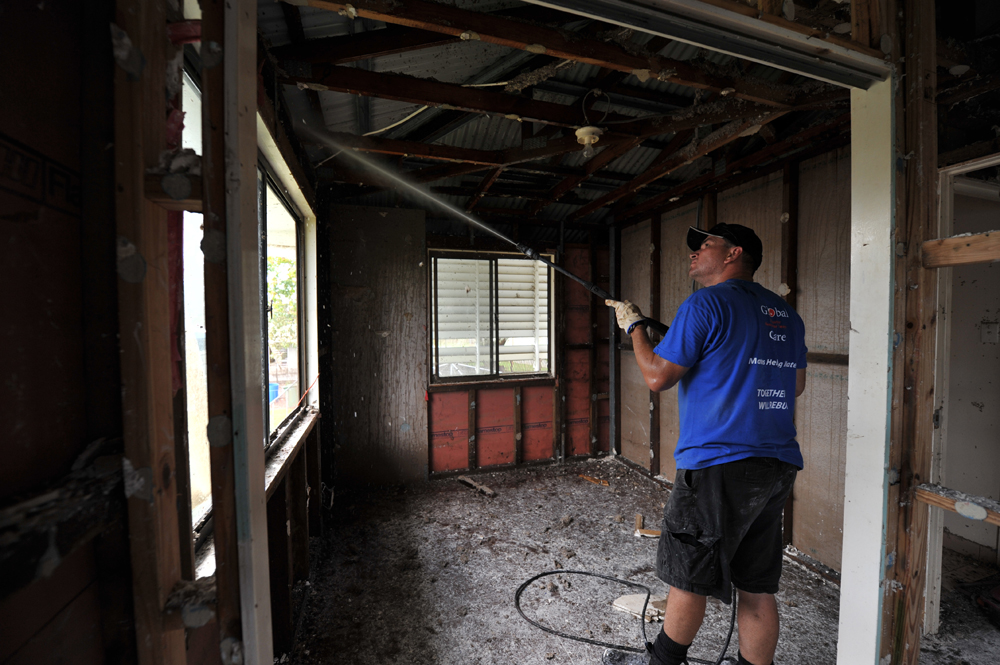 Global Care Volunteer Craig Knowles of Horsley, uses a gurney to wash down the framework of a house in North Booval, Queensland.